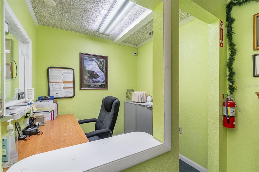 A small office with lime green walls, a wooden desk, and a black rolling chair — 6005 SILVER STAR ROAD, ORLANDO, FL