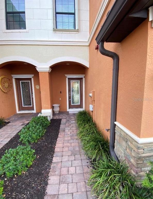 A paved walkway leads to two front doors under arched entryways of a stucco building — 20270 LA GENTE CIRCLE, VENICE, FL
