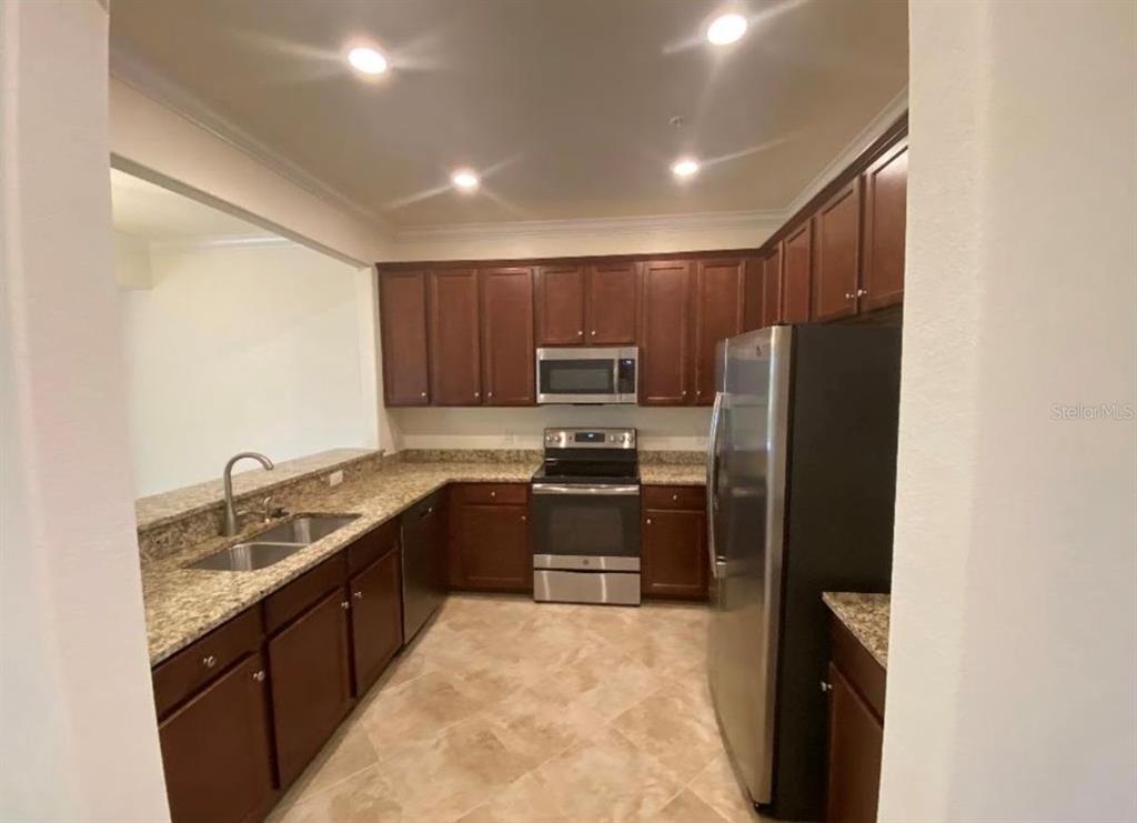 A kitchen with dark wood cabinets, granite countertops, and stainless steel appliances — 20270 LA GENTE CIRCLE, VENICE, FL