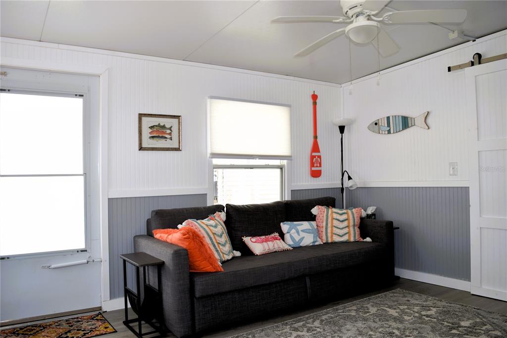 A living room features a dark gray sofa, beadboard walls, and coastal-themed decor — 79 EAGLE POINT S, OSTEEN, FL