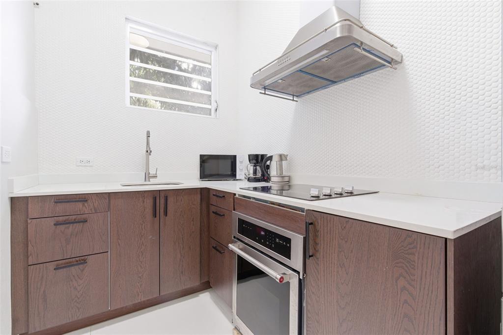 A modern kitchen features dark wood cabinets, white countertops, a stainless steel oven, and range — 56 CALLE F KRUG CONDADO UNIT 4, SAN JUAN, PR