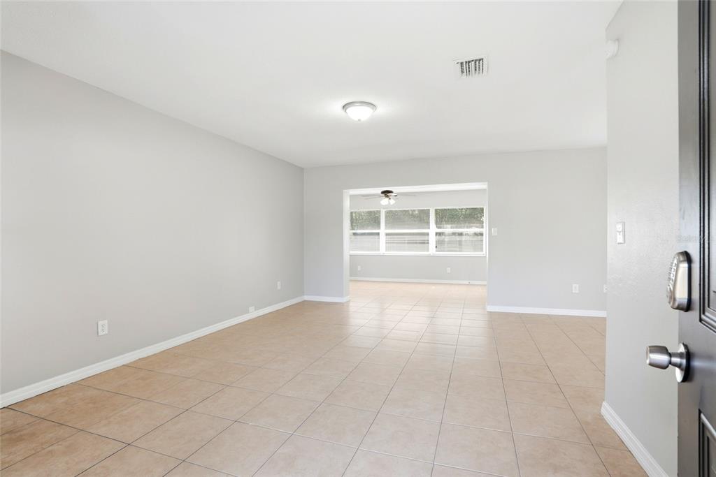 An interior view of a living room with light gray walls and tan tile flooring — 301 TERRACE DRIVE E, CLEARWATER, FL