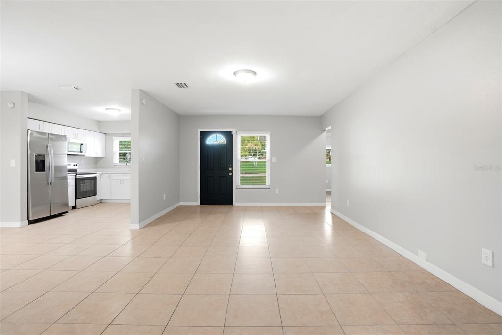 A bright, open-concept living area with light tile flooring, gray walls, and an adjacent kitchen — 301 TERRACE DRIVE E, CLEARWATER, FL