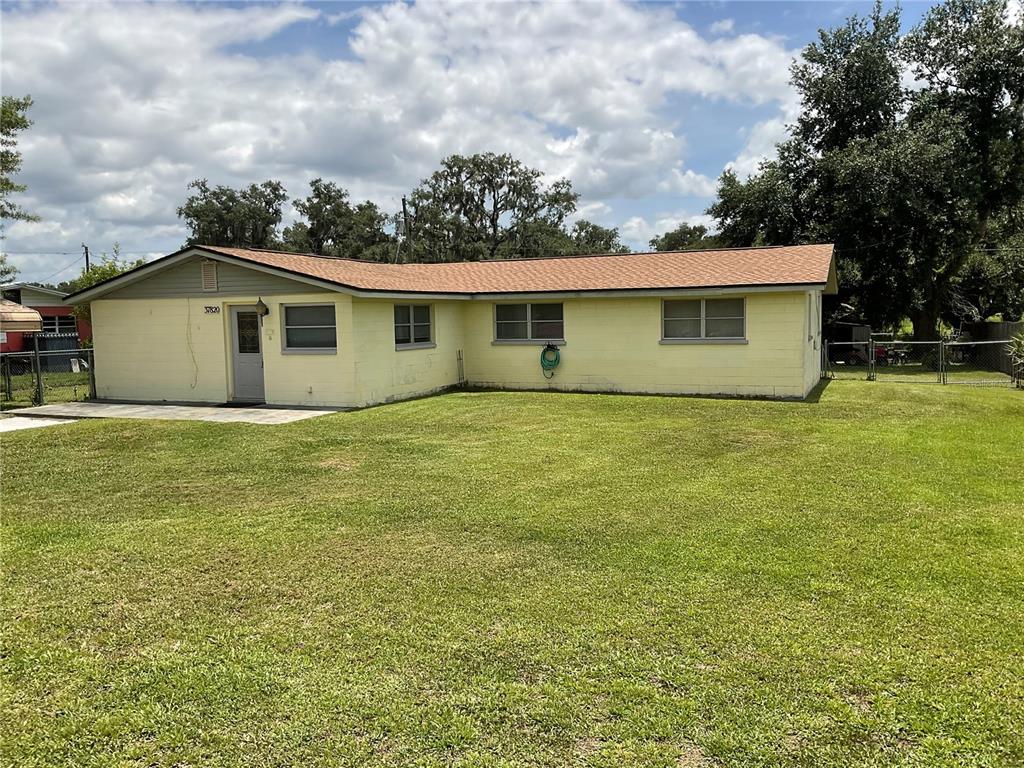 A single-story yellow house with a brown roof sits on a large grassy lot — 37820 CRYSTAL WAY, DADE CITY, FL
