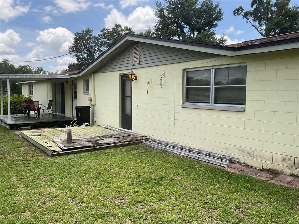 The exterior of a light yellow concrete block house features a deck and a ladder — 37820 CRYSTAL WAY, DADE CITY, FL