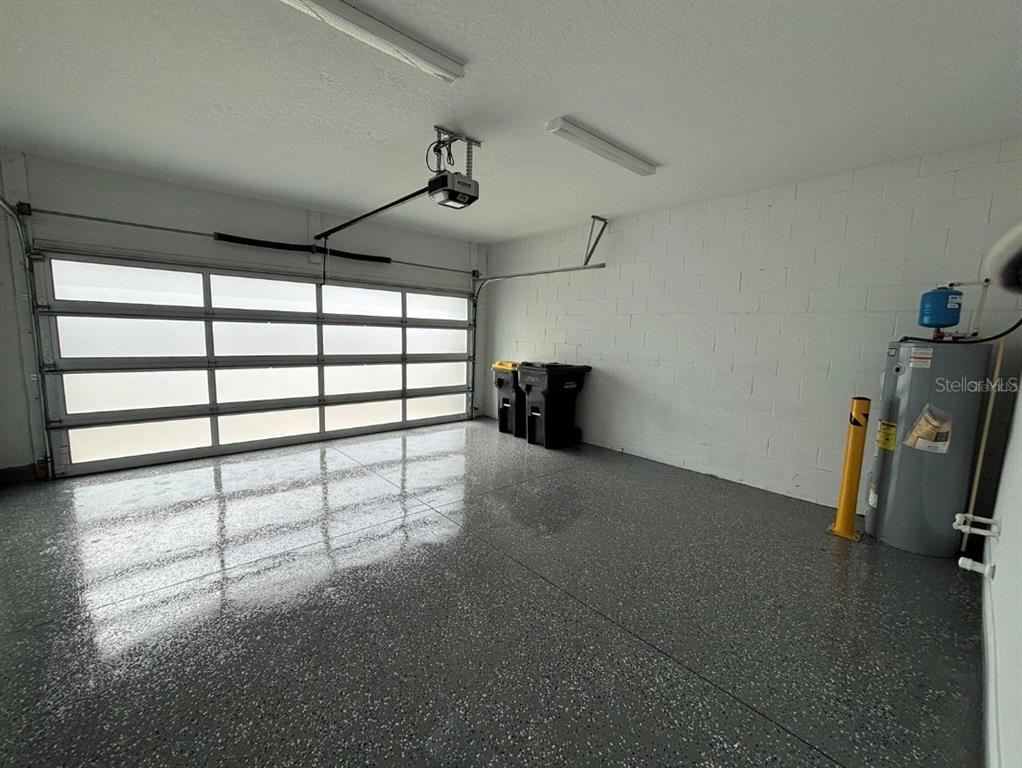 A garage with a gray epoxy floor, a sectional glass door, and a water heater — 1915 GREENBRIAR TERRACE, DAVENPORT, FL