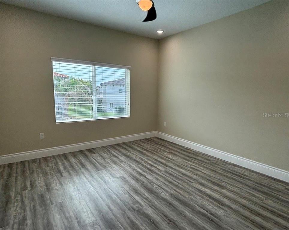 An empty bedroom features light-colored walls, wood-look flooring, a ceiling fan, and a window — 1915 GREENBRIAR TERRACE, DAVENPORT, FL