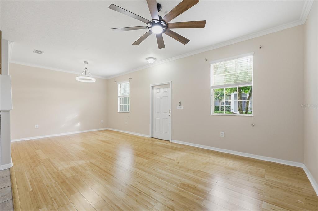 An empty living room with light wood flooring, a ceiling fan, and two windows — 1351 VASEY ROAD, APOPKA, FL