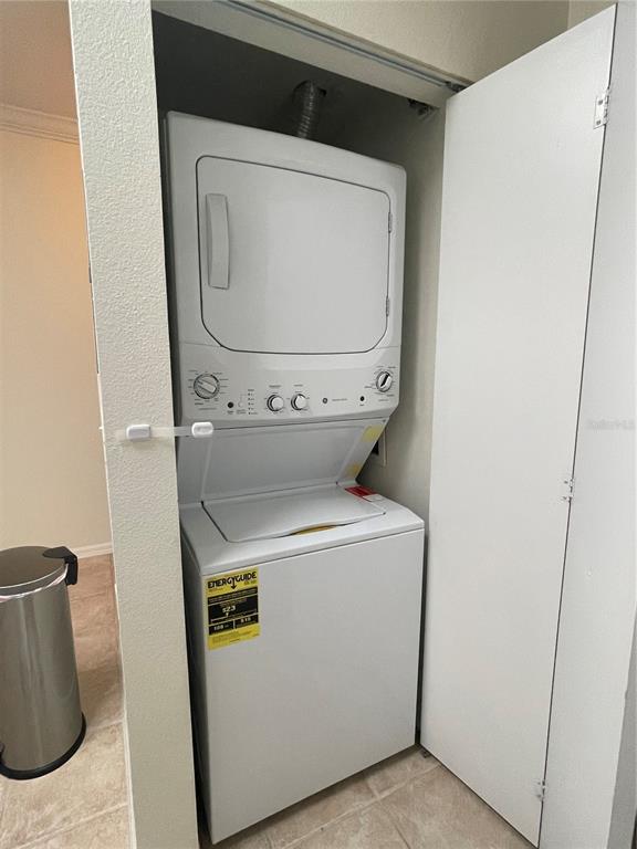 A white stacked washer and dryer unit sits inside a small closet — 9172 SW 52ND ROAD UNIT F202, GAINESVILLE, FL