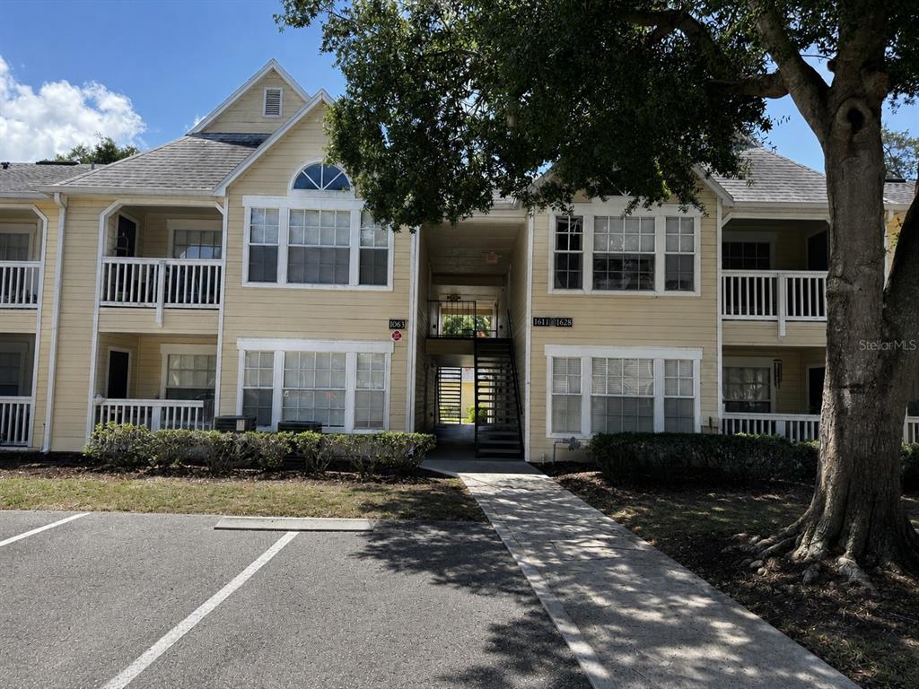 A two-story yellow apartment building features balconies, large windows, and a central outdoor staircase — 1063 S HIAWASSEE ROAD UNIT 1628, ORLANDO, FL
