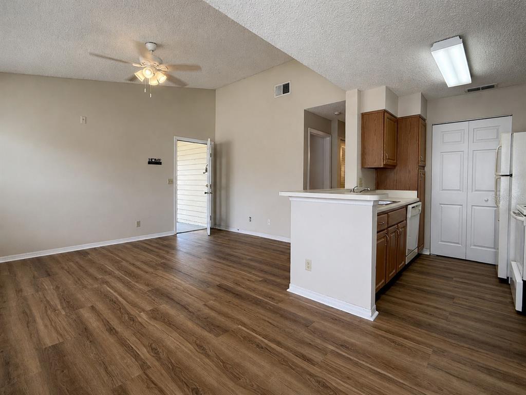 An open-concept living area features wood-look flooring, a ceiling fan, and an adjacent kitchen — 1063 S HIAWASSEE ROAD UNIT 1628, ORLANDO, FL