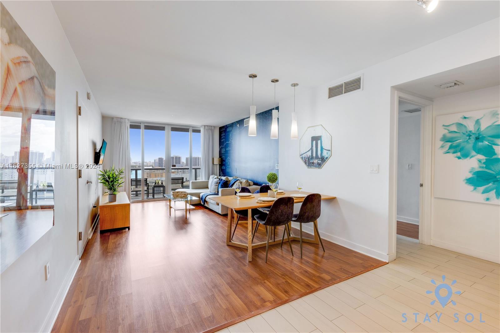A living and dining area features wood flooring, a blue accent wall, and balcony access — 2602 E Hallandale Beach Blvd # R2009, Hallandale Beach FL 33009, HALLANDALE BEACH, FL