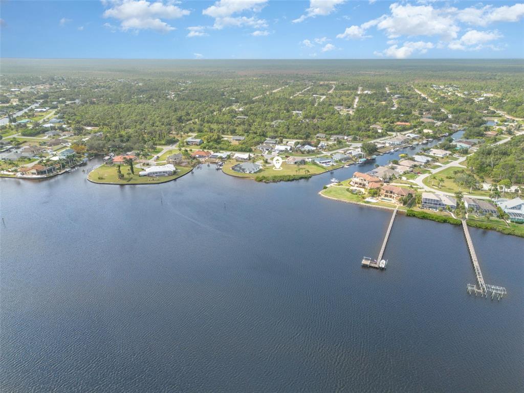An aerial view shows waterfront homes with private docks along a canal and large bay — 3528 FOX TERRACE, PORT CHARLOTTE, FL