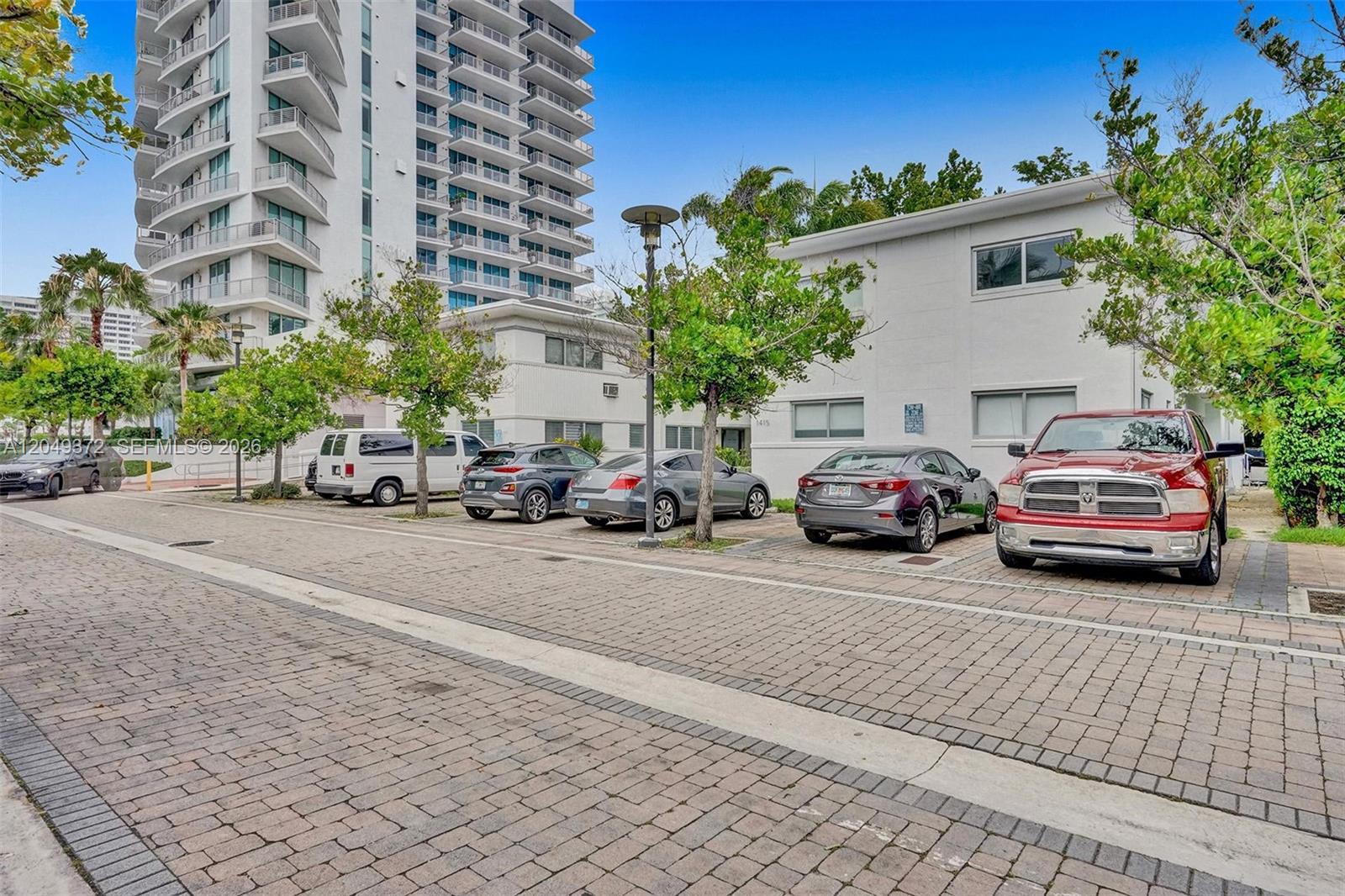 A parking lot with several cars sits in front of a white multi-story building — 1415 16th St # 2, Miami Beach FL 33139, MIAMI BEACH, FL