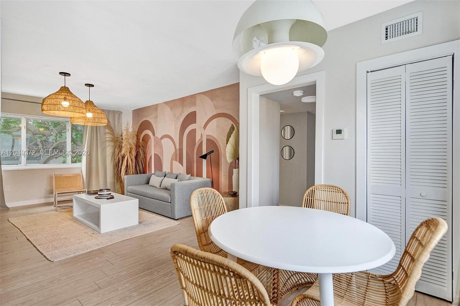 A living and dining area features a mural wall, rattan chairs, and pendant lighting — 1415 16th St # 2, Miami Beach FL 33139, MIAMI BEACH, FL