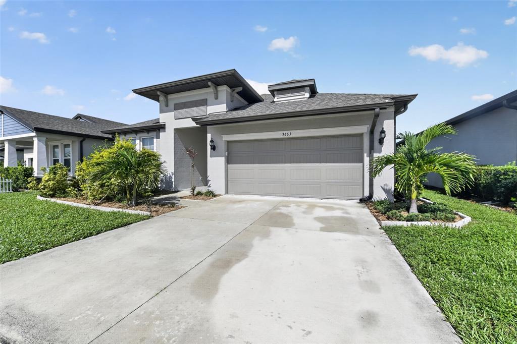 A single-story house with a gray garage, stucco exterior, and a palm tree in front — 3663 QUIET DRIVE, SARASOTA, FL