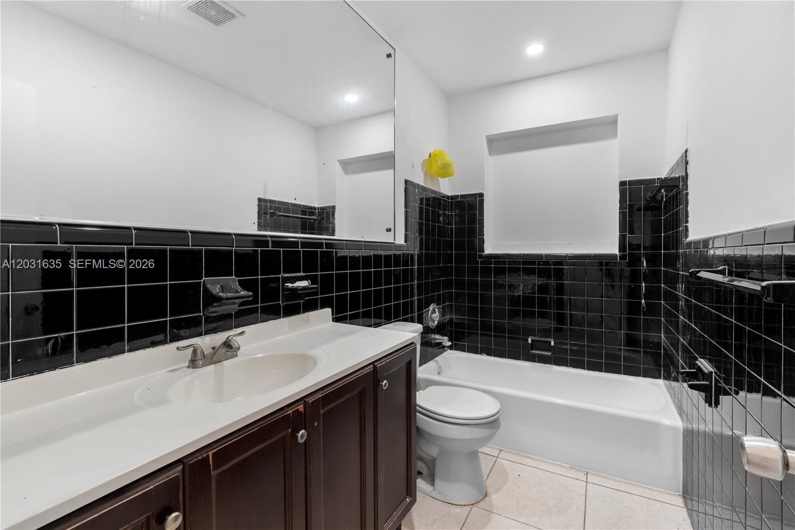 A bathroom features a dark wood vanity, a white sink, and black tiled walls — 3061 NE 4th Ave, Wilton Manors FL 33334, WILTON MANORS, FL