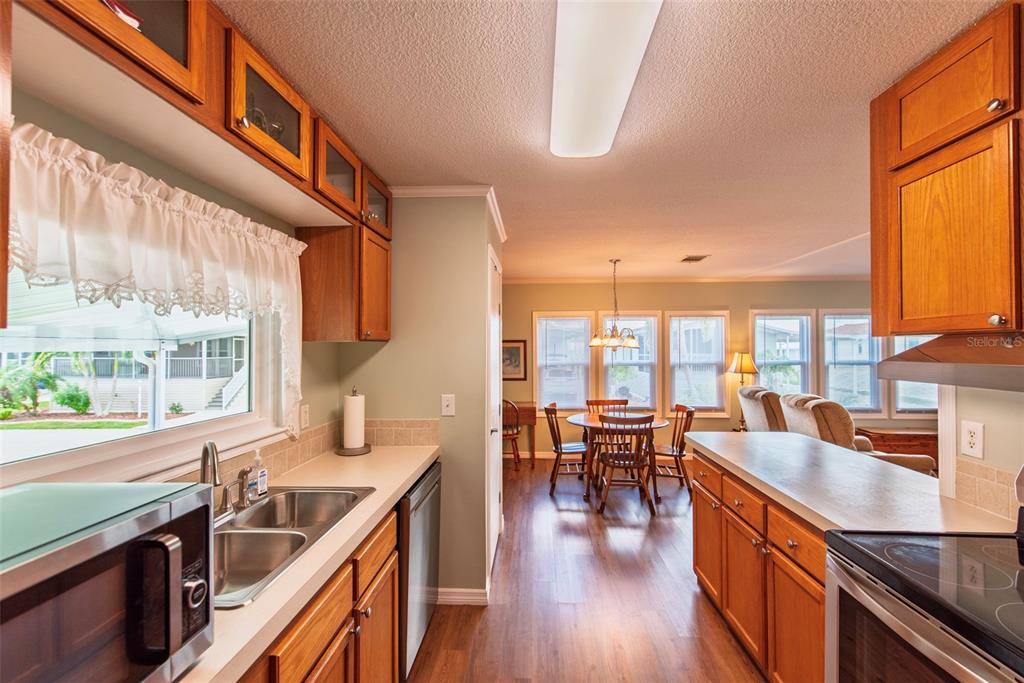 A kitchen with wood cabinets and a sink overlooks a dining area and living room — 21 BRINK AVENUE, PUNTA GORDA, FL