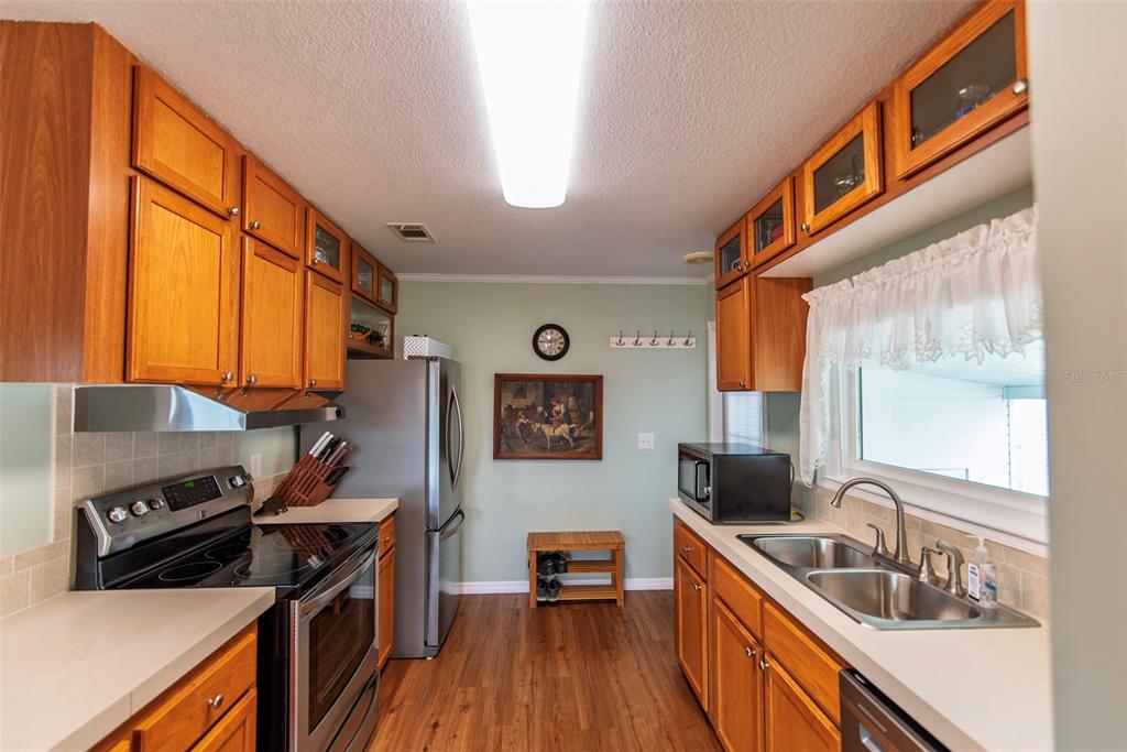 A kitchen features wood cabinets, stainless steel appliances, a double sink, and light green walls — 21 BRINK AVENUE, PUNTA GORDA, FL