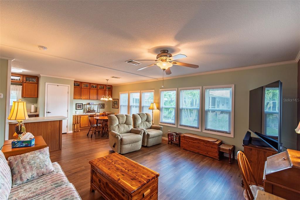 A living room with wood-look flooring, two recliners, a television, and an adjacent dining area — 21 BRINK AVENUE, PUNTA GORDA, FL