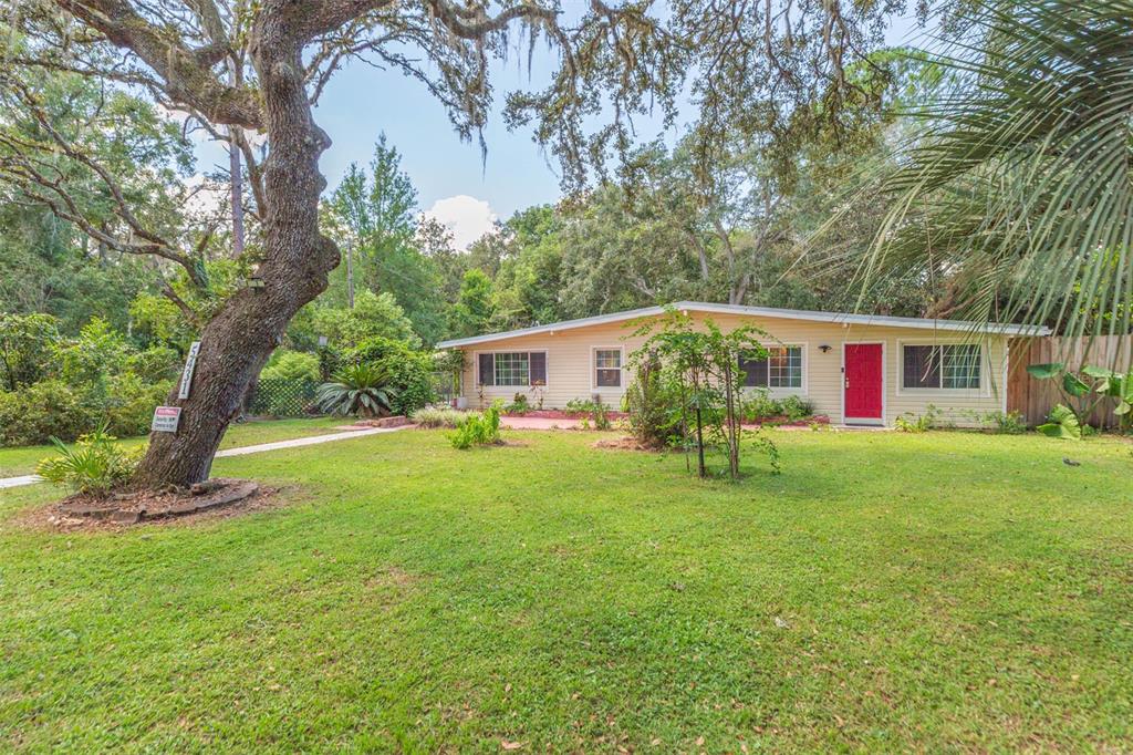 A single-story house with yellow siding and a red front door sits on a lawn — 5431 TOWER STREET, DADE CITY, FL