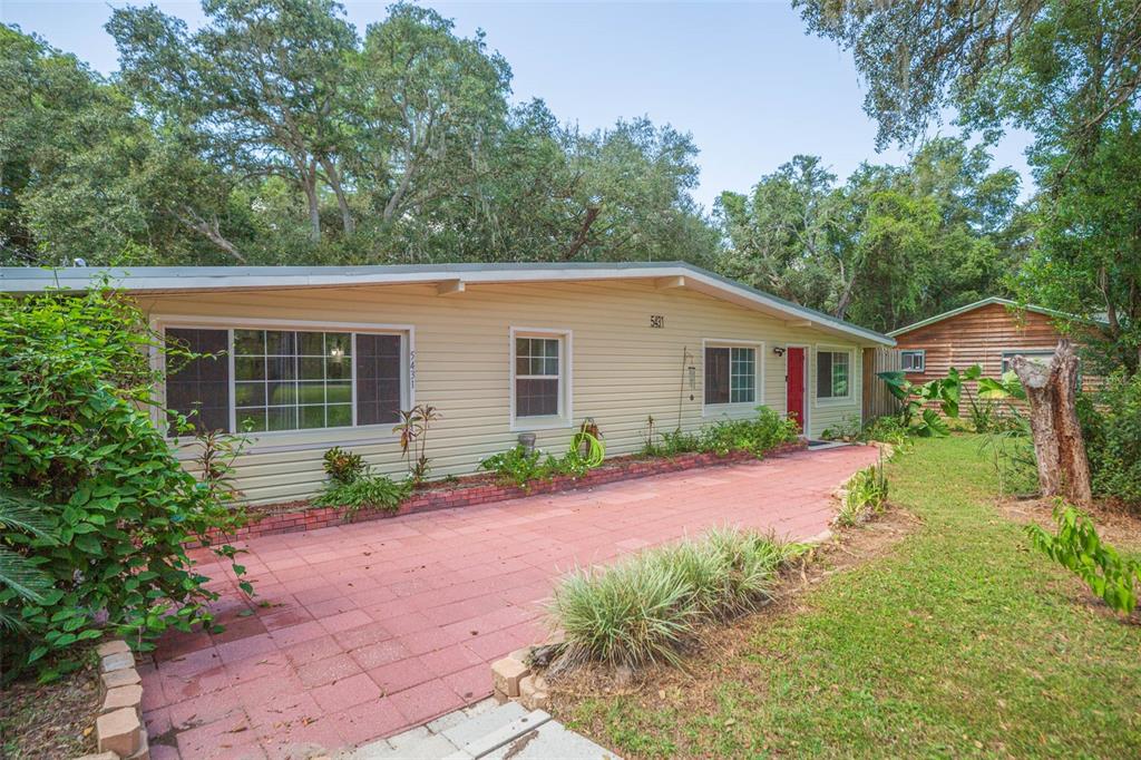 A single-story house with beige siding, a red brick patio, and a red front door — 5431 TOWER STREET, DADE CITY, FL
