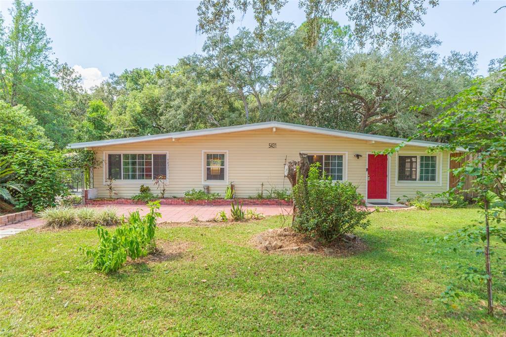 A single-story house with light yellow siding, a red front door, and a brick patio — 5431 TOWER STREET, DADE CITY, FL