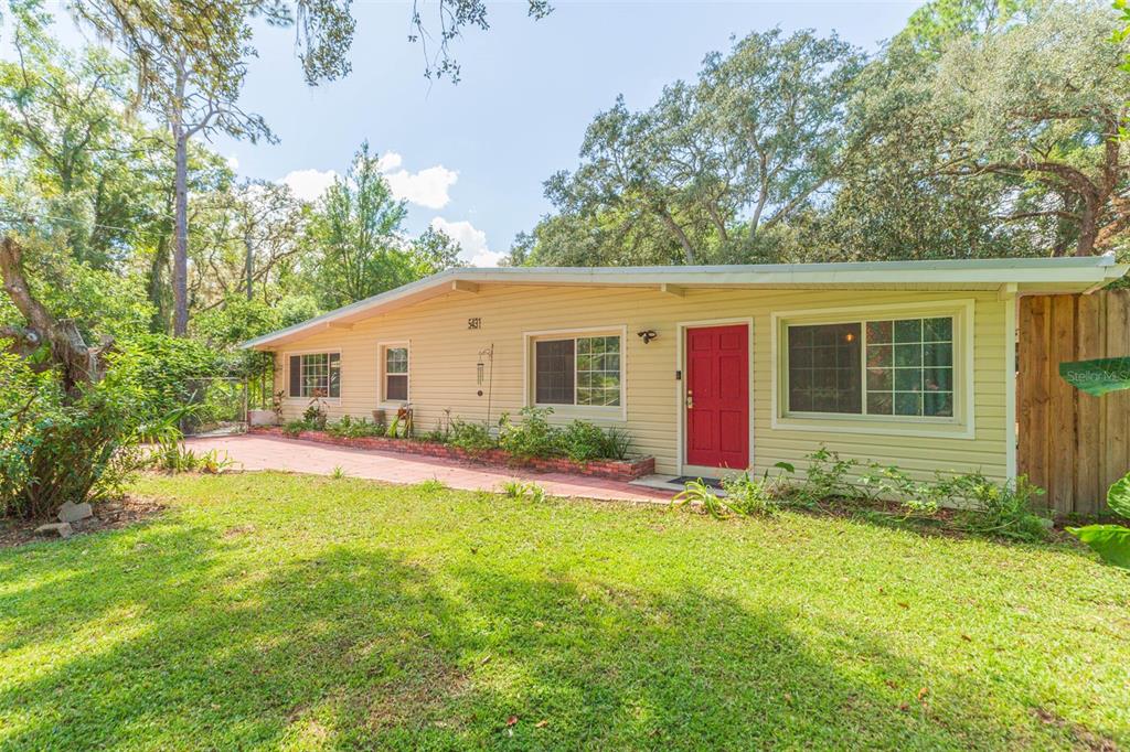 A single-story house with light-colored siding, a red front door, and a brick patio — 5431 TOWER STREET, DADE CITY, FL