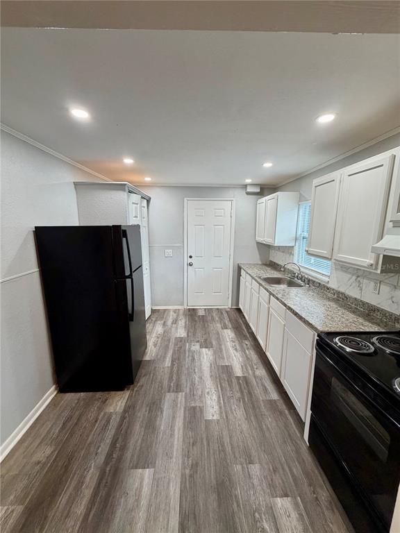 A kitchen features white cabinets, granite countertops, a black refrigerator, and wood-look flooring — 908 BEVERLY AVENUE UNIT F, LARGO, FL