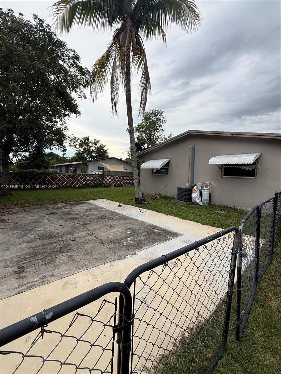 A concrete patio sits in a backyard with a palm tree and chain-link fence — 300 SW 9th Ave # A, Hallandale Beach FL 33009, HALLANDALE BEACH, FL