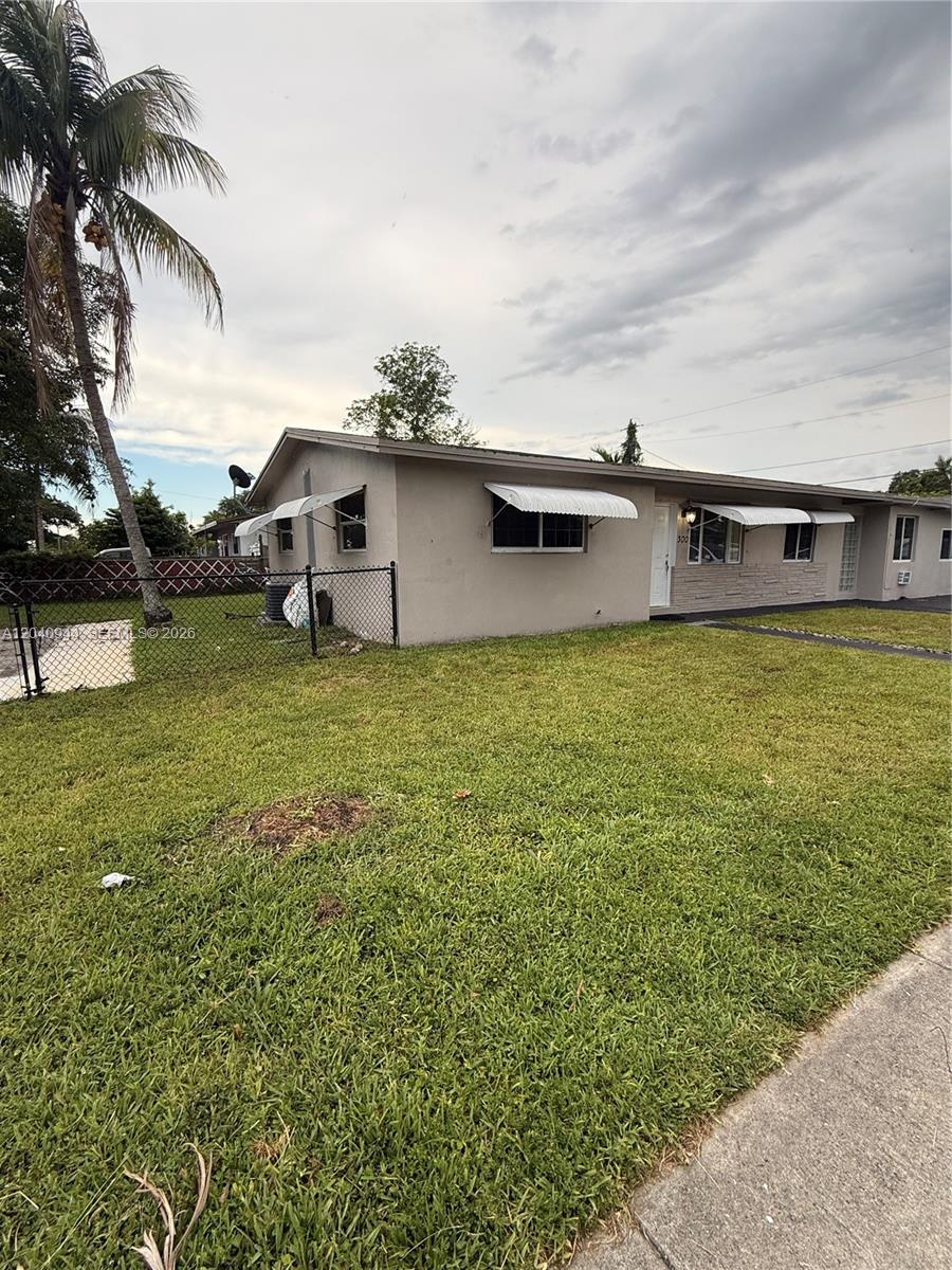 A single-story house with a beige exterior, metal window awnings, and a chain-link fence — 300 SW 9th Ave # A, Hallandale Beach FL 33009, HALLANDALE BEACH, FL