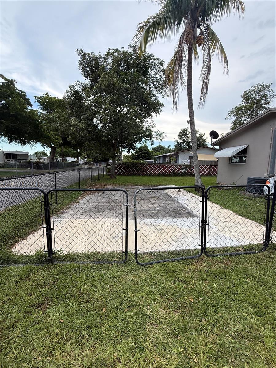 A fenced-in concrete patio area sits in a backyard next to a house — 300 SW 9th Ave # A, Hallandale Beach FL 33009, HALLANDALE BEACH, FL