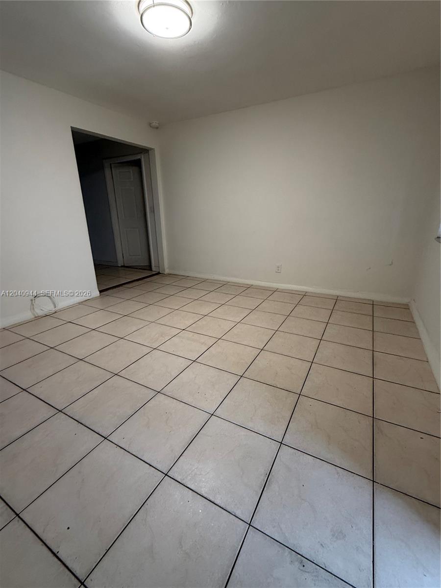 An empty room features white walls, a flush-mount ceiling light, and light-colored square floor tiles — 300 SW 9th Ave # A, Hallandale Beach FL 33009, HALLANDALE BEACH, FL