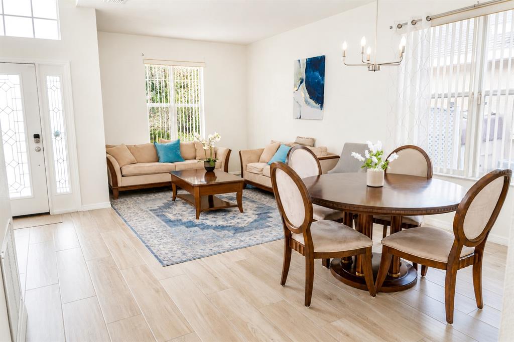 A living and dining area features light wood-look tile floors, neutral furniture, and a rug — 10118 CYPRESS KNEE CIRCLE, ORLANDO, FL