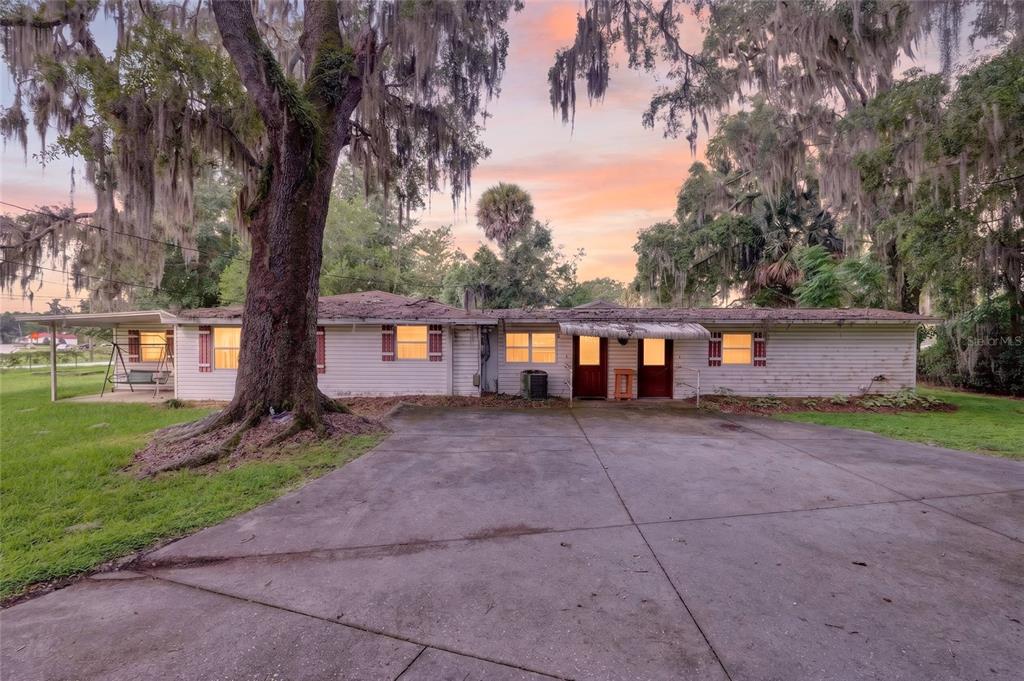 A single-story house with white siding, a concrete driveway, and large trees with Spanish moss — 6141 SE BABB ROAD, BELLEVIEW, FL