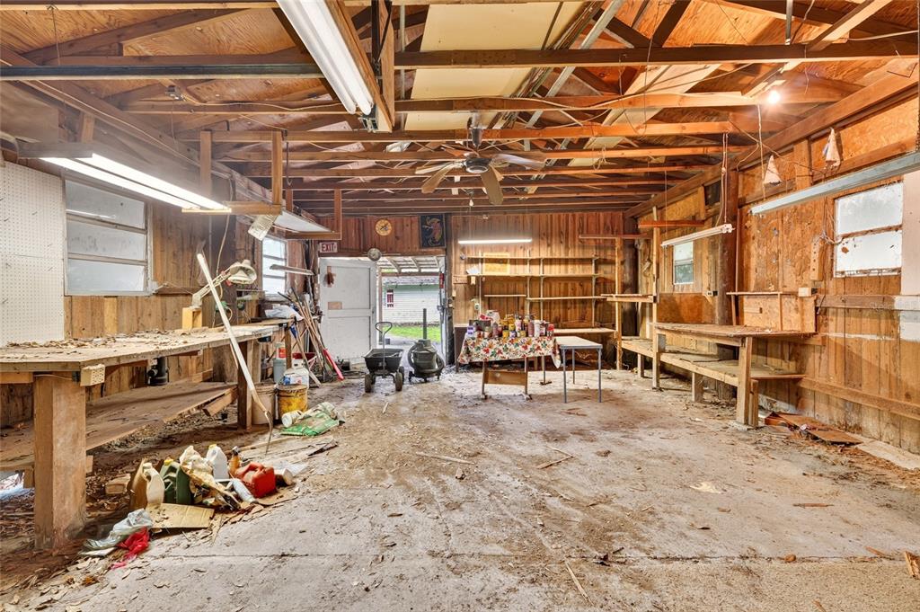 A rustic, unfinished wooden workshop with workbenches, exposed rafters, and a concrete floor — 6141 SE BABB ROAD, BELLEVIEW, FL
