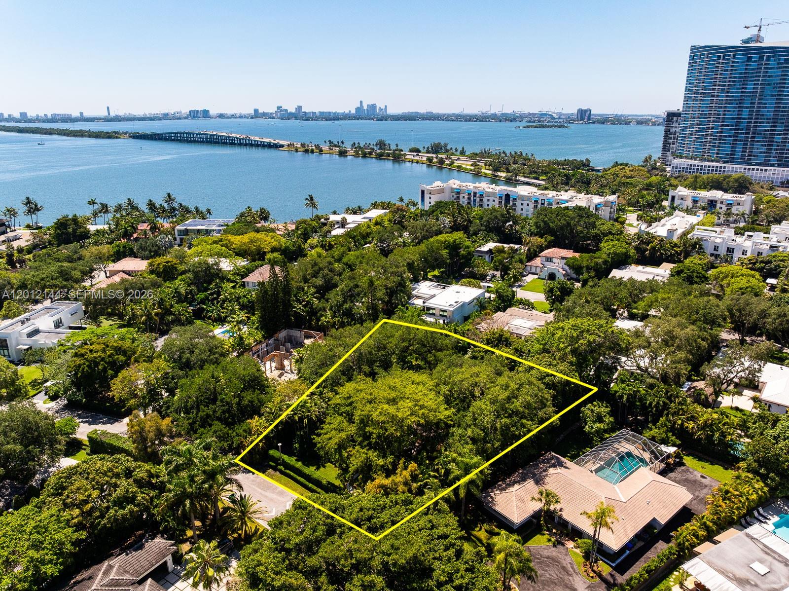 An aerial view shows a wooded, rectangular residential lot outlined in yellow near a bay — 530 Melaleuca Ln, Miami FL 33137, MIAMI, FL