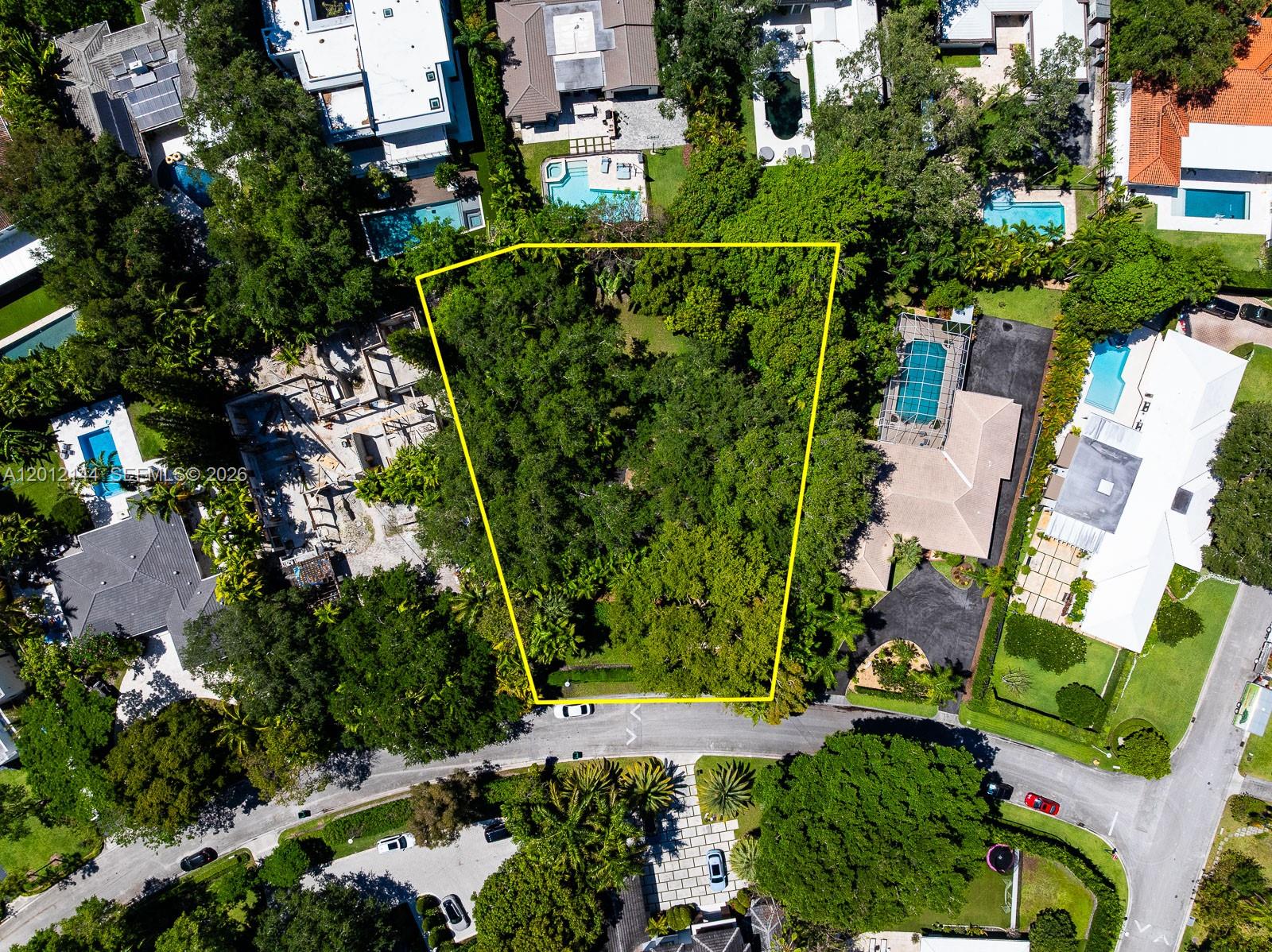 An aerial view shows a vacant, tree-covered residential lot outlined in yellow between two houses — 530 Melaleuca Ln, Miami FL 33137, MIAMI, FL