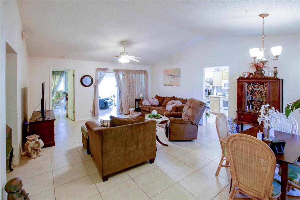 A living room with tile floors, brown furniture, and an adjacent dining area — 7403 HEATHER WALK DRIVE, WEEKI WACHEE, FL