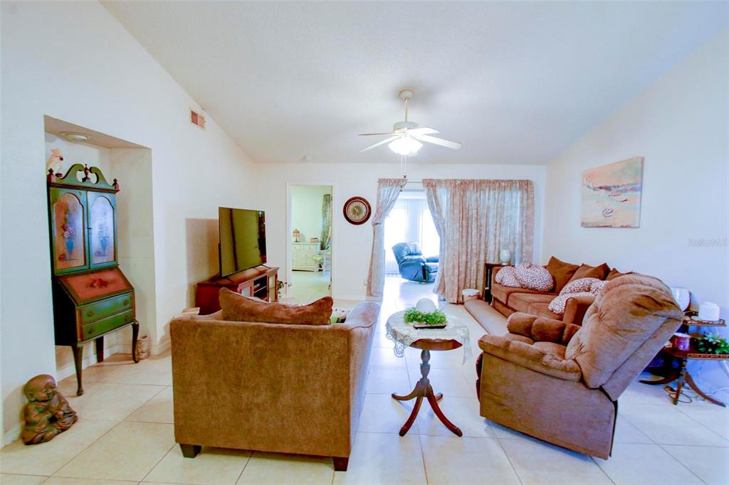 A living room features tile flooring, a ceiling fan, brown furniture, and a green hutch — 7403 HEATHER WALK DRIVE, WEEKI WACHEE, FL
