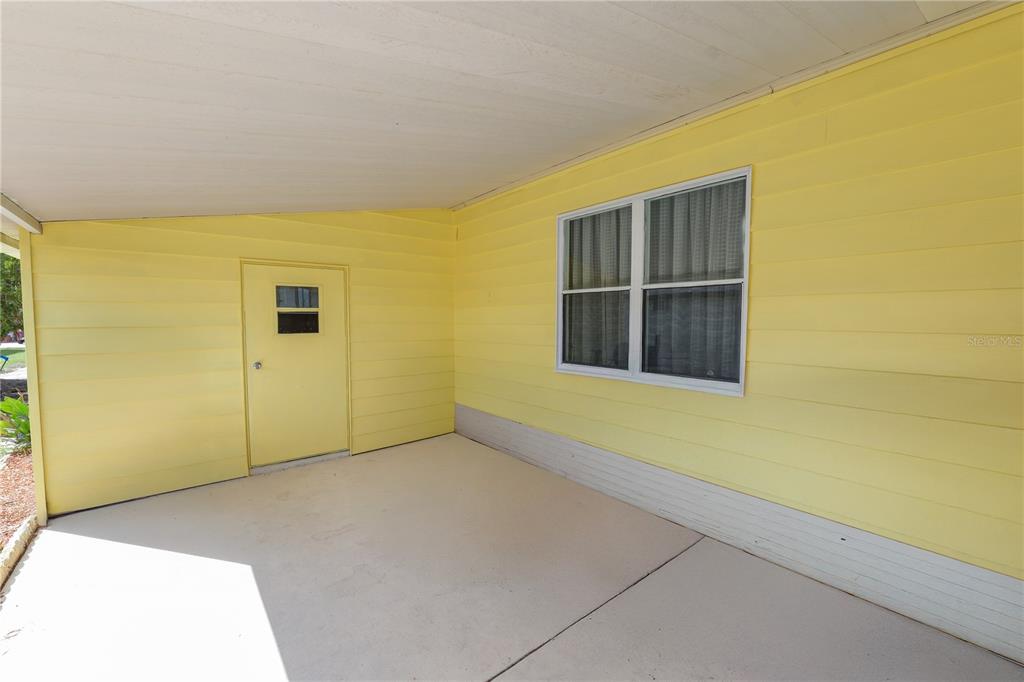 A covered patio with yellow horizontal siding, a single door, and a white-framed window — 5026 FOXWOOD BOULEVARD, LAKELAND, FL
