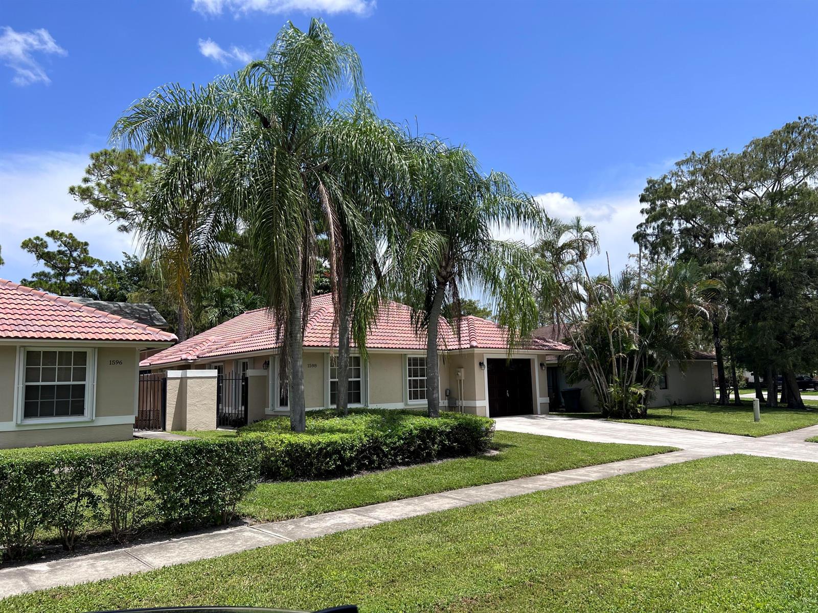 A tan single-story house with a red tile roof and palm trees in the front yard — 1598 Hawthorne Place, Wellington FL 33414, WELLINGTON, FL