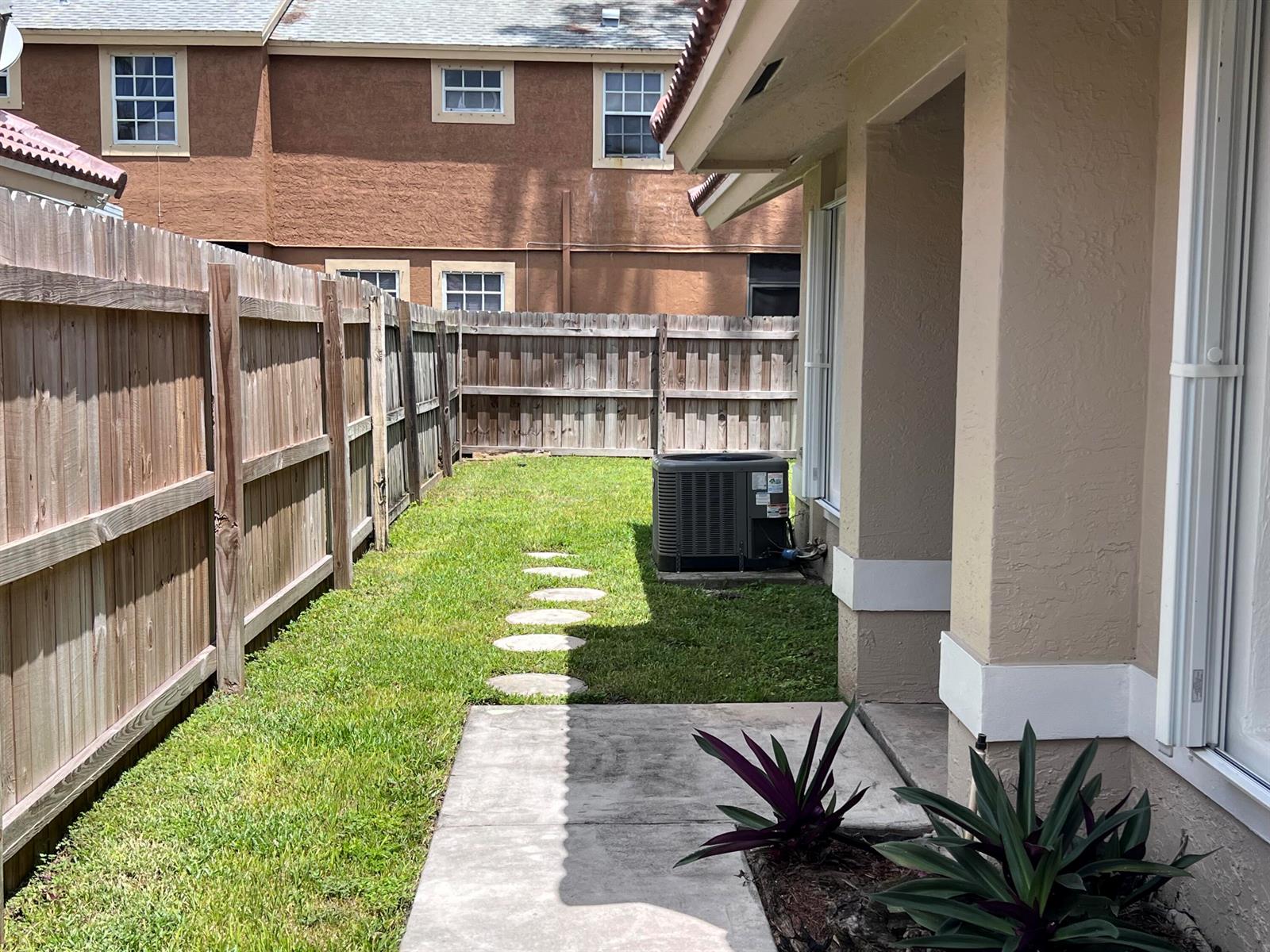 A side yard features a concrete walkway, a wooden fence, and an outdoor air conditioning unit — 1598 Hawthorne Place, Wellington FL 33414, WELLINGTON, FL