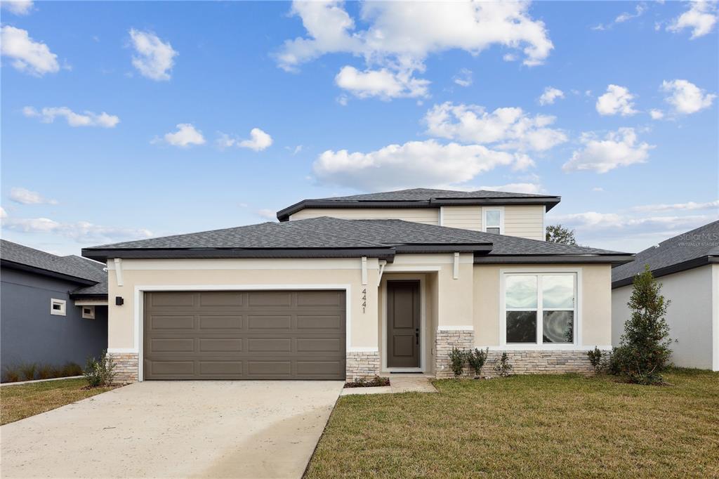 A two-story suburban house with a beige stucco exterior, stone accents, and a two-car garage — 90 SPRINGWOOD DRIVE, PALM COAST, FL