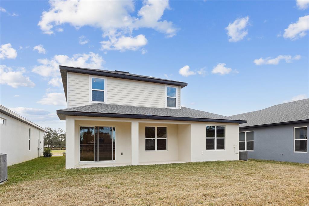 The exterior rear view of a two-story house features a covered patio and lawn — 90 SPRINGWOOD DRIVE, PALM COAST, FL