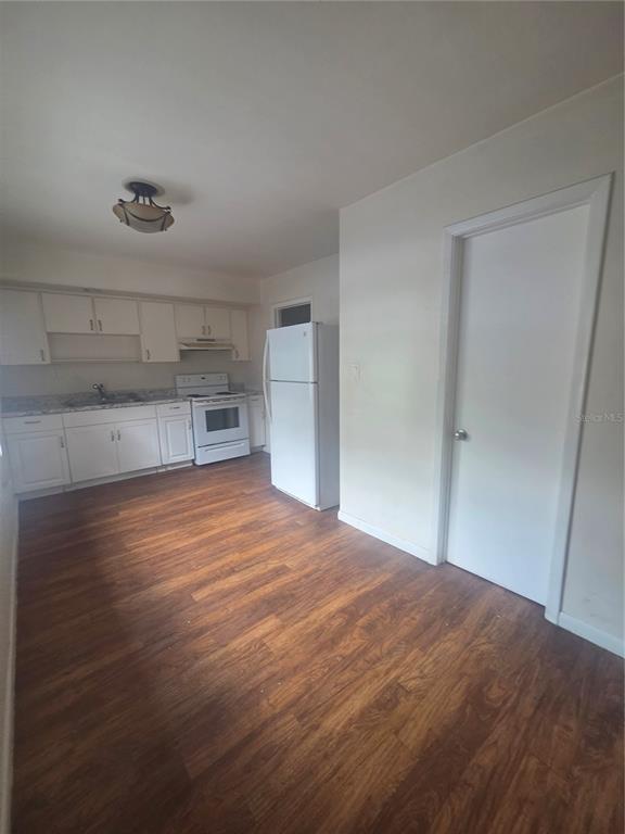 A kitchen features white cabinets, white appliances, and wood-look flooring — 572 BELL, BROOKSVILLE, FL