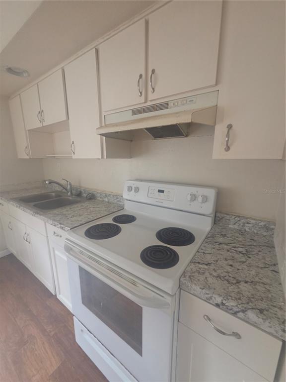 A kitchen features white cabinets, granite countertops, a double sink, and a white electric stove — 572 BELL, BROOKSVILLE, FL