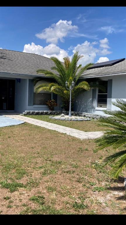 A single-story house exterior features a palm tree, a stone walkway, and a lamp post — 303 COCOA COURT, KISSIMMEE, FL