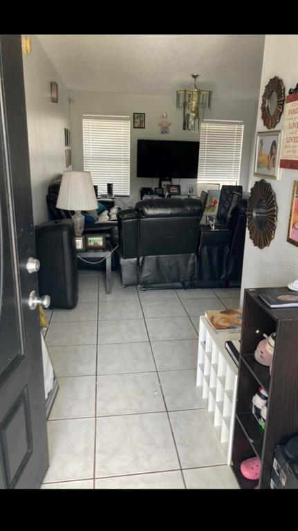 A living room features light tile flooring, a black leather recliner, and a wall-mounted television — 303 COCOA COURT, KISSIMMEE, FL