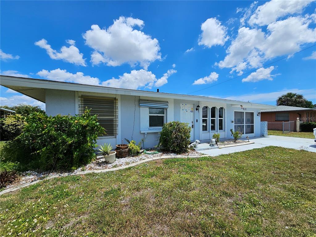 A single-story house with a light gray exterior, a flat roof, and a front lawn — 531 AZALEA DRIVE NW, PORT CHARLOTTE, FL
